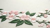 Delicate pink cherry blossom embroidery with green leaves on cream fabric showcasing traditional needlework craftsmanship for textile and craft projects.