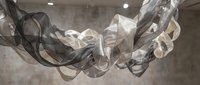 Elegant flowing transparent fabric ribbons creating dynamic movement against soft gray background for luxury fashion and textile design projects.