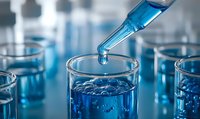 Laboratory pipette dropping blue liquid into glass test tube, creating ripple effect in solution. Scientific research and chemical analysis concept.