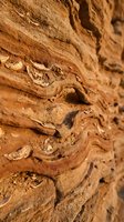 Layered sandstone rock formation with natural erosion patterns and weathered texture showing geological stratification and desert landscape features.