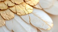Delicate white feathers adorned with shimmering gold leaf create an ethereal macro composition showing natural texture and luxury design elements.