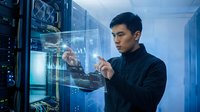 Young Asian male IT professional in dark clothing interacting with holographic data interface in server room environment for technology and digital innovation concepts.