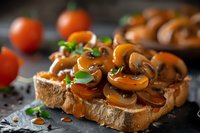 Sauteed mushrooms on toasted bread garnished with fresh herbs and cherry tomatoes, served on dark stone background. Close up view of appetizing bruschetta.