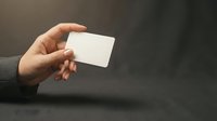 Hand holding a blank white card on dark background, mockup with copy space for branding, business, or identity design presentation.