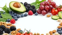 Fresh organic fruits vegetables nuts arranged in circle on white background creating healthy eating frame with copy space for nutritious diet concepts.