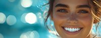 Young Caucasian woman with bright white smile and blue eyes against turquoise bokeh background, radiating happiness and positive energy in summer sunlight.