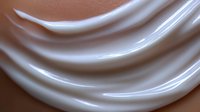 Smooth silky fabric waves in soft beige and white tones create elegant flowing curves with gentle highlights and shadows. Luxurious textile background.