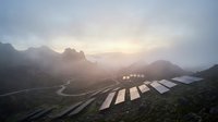 Solar panel farm in misty mountain valley at sunrise with renewable energy infrastructure and dramatic landscape lighting effects.