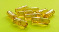 Golden yellow vitamin capsules scattered on bright green background for health and wellness supplement marketing materials.