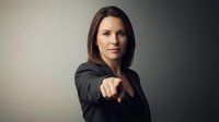 Confident Caucasian businesswoman pointing finger directly at camera with serious expression, dark studio background, leadership concept.