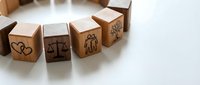 Wooden blocks with engraved symbols representing justice, family, and social values arranged in row on white surface for legal and ethical concepts.