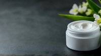 White cosmetic cream jar with delicate flowers on dark stone background, luxury skincare product photography for beauty and wellness marketing.