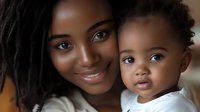 African American mother with dreadlocks smiling warmly while holding her adorable toddler son in bright natural lighting for family lifestyle content.