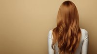 Back view of woman with long wavy auburn hair wearing white top against beige background, showcasing healthy hairstyle.