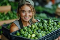 Young female farmer holding fresh harvested brussels sprouts in crate at organic farm. Sustainable agriculture and local food production concept.