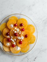 Fresh persimmon carpaccio garnished with cranberries and feta cheese crumbles on marble background, elegant appetizer presentation for fine dining.