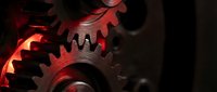 Industrial metal gears with dramatic red lighting showcasing precision engineering and mechanical power for manufacturing and technology concepts.