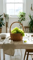 Wicker basket filled with fresh green grapes on wooden table in bright sunlit room with potted plants and window view, suitable for food styling and home decor projects.