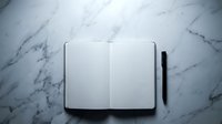 Open blank notebook with black pen on white marble surface for writing, journaling, planning and creative work.