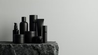 Black cosmetic bottles and containers arranged on dark stone surface against neutral background for luxury skincare and beauty product branding.