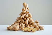 Fresh ginger root pile with sliced pieces on white surface against neutral gray background for cooking, health, and wellness concepts.