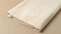 Folded natural linen fabric in cream tone on neutral background, suitable for textile, home decor, and fashion design projects.