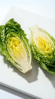 Fresh savoy cabbage halves cut lengthwise showing detailed inner leaves and texture on white background for healthy cooking and nutrition concepts.