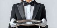 Professional waiter in formal black tuxedo and white gloves holding empty silver serving tray, ready for luxury restaurant service.