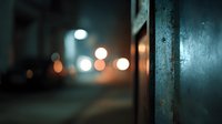 Urban night scene with blurred city lights and bokeh effect through metal structure. Atmospheric street photography with warm glowing orbs and cool tones.
