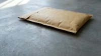 Kraft paper padded mailer envelope lying on gray concrete surface, eco-friendly packaging solution for safe shipping and delivery.