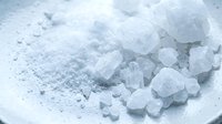 Sea salt crystals and fine powder on white surface, suitable for culinary, cosmetic, and wellness product photography and packaging design.