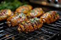 Grilled chicken wings with caramelized glaze and fresh herbs on barbecue grate, showing char marks and glistening sauce. Close up view captures juicy texture.