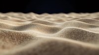 Close-up macro view of desert sand dunes with soft curves and natural texture patterns creating abstract landscape in warm beige tones against dark background.