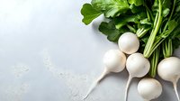 Fresh white round turnips with bright green leaves on light gray concrete background with copy space for menu or recipe design.
