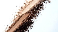 Diagonal smear of loose face powder or bronzer with scattered particles on white background, isolated cosmetic texture for beauty and makeup design.