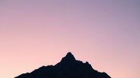 Mountain silhouette against pink and purple twilight sky, suitable for backgrounds, nature themes, and landscape design projects.