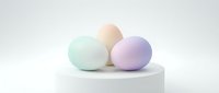 Pastel colored Easter eggs in soft mint green, peach and lavender purple arranged on white pedestal against neutral background for spring holiday decor.