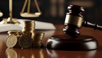Wooden gavel with gold coins and scales of justice on desk representing legal fees, court costs, financial litigation, and attorney expenses.