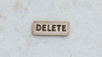 Vintage paper label with word DELETE on textured white background. Minimalist composition for design and technology concepts.