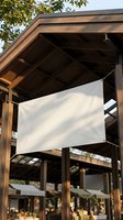 Blank white fabric banner hanging on wooden pavilion structure outdoors, mockup for advertising, event signage, or promotional display design.
