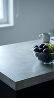 Fresh grapes in glass bowl on concrete countertop with minimalist kitchen interior, natural window light, suitable for food and lifestyle design projects.