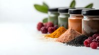 Colorful superfoods and smoothie ingredients with powder supplements, chia seeds, turmeric, cacao, fresh raspberries and glass jars of healthy drinks.