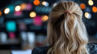 Blonde woman with half-up hairstyle looking away against blurred bokeh lights background. Soft focus romantic evening atmosphere with colorful defocused city lights.