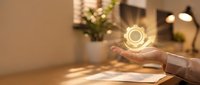 Businesswoman holding glowing light bulb icon above desk, representing innovation, creativity, and sustainable energy solutions for corporate success.