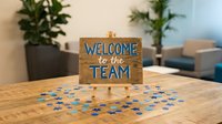 Wooden welcome to the team sign on office desk with colorful confetti, perfect for new employee onboarding and workplace celebration concepts.