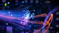 Fiber optic cables with glowing light streams in blue and orange colors showing high-speed data transmission and network connectivity technology.