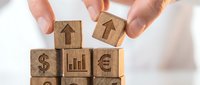 Business growth concept with wooden blocks featuring financial symbols and upward arrows being arranged by hands on white background.