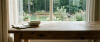 Wooden desk with bowl and papers near bright window overlooking garden, suitable for home office, workspace, and interior design projects.
