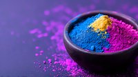 Vibrant blue, yellow and pink powder pigments in black ceramic bowl on purple background with scattered color dust, macro photography for cosmetic and art.