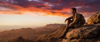 Male hiker sitting on rocky mountain peak at sunset, contemplating vast landscape below. Adventure, travel, and outdoor exploration concept for lifestyle and wellness projects.